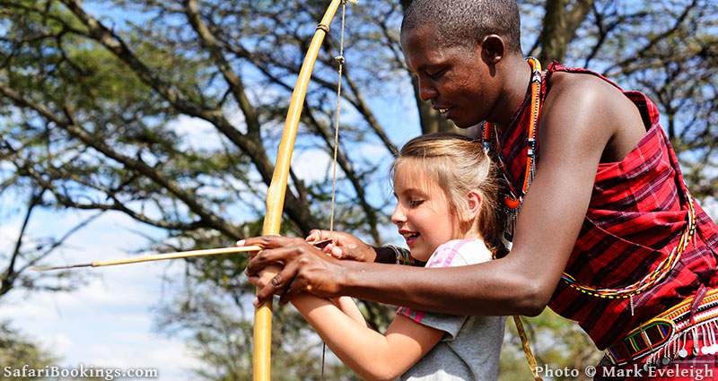 10 year old Lucia learns to shoot a Maasai bow at Naboisho Camp on the edge of the Masai Mara