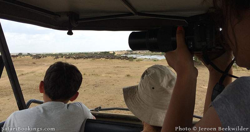 Family watching the wildebeest migration on a private safari in the Serengeti, Tanzania