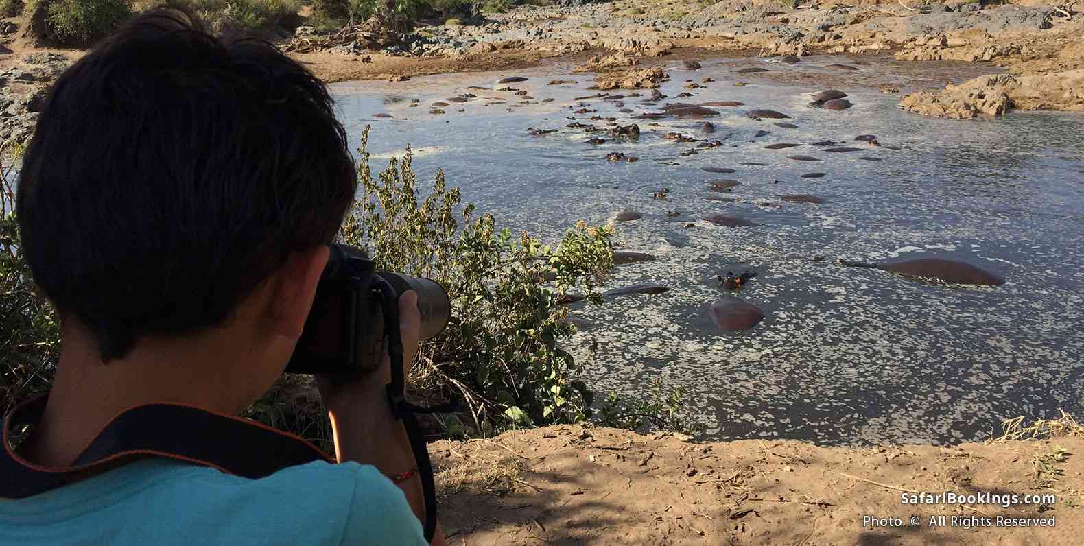 Boy with photo camera at Hippo pool at Serengeti National Park