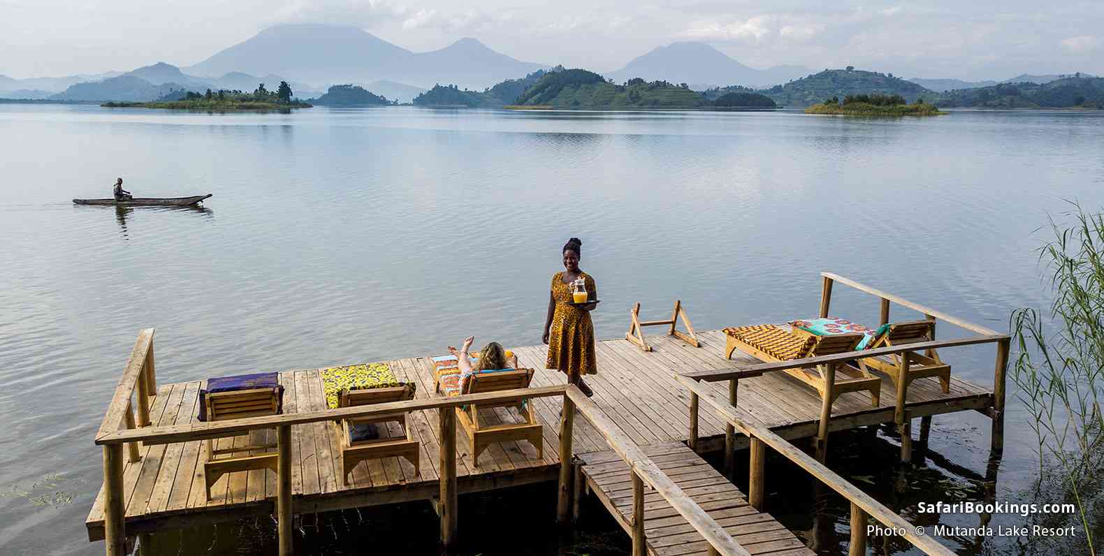 Women on the dock at Mutanda Lake Resort, with mountains in the background
