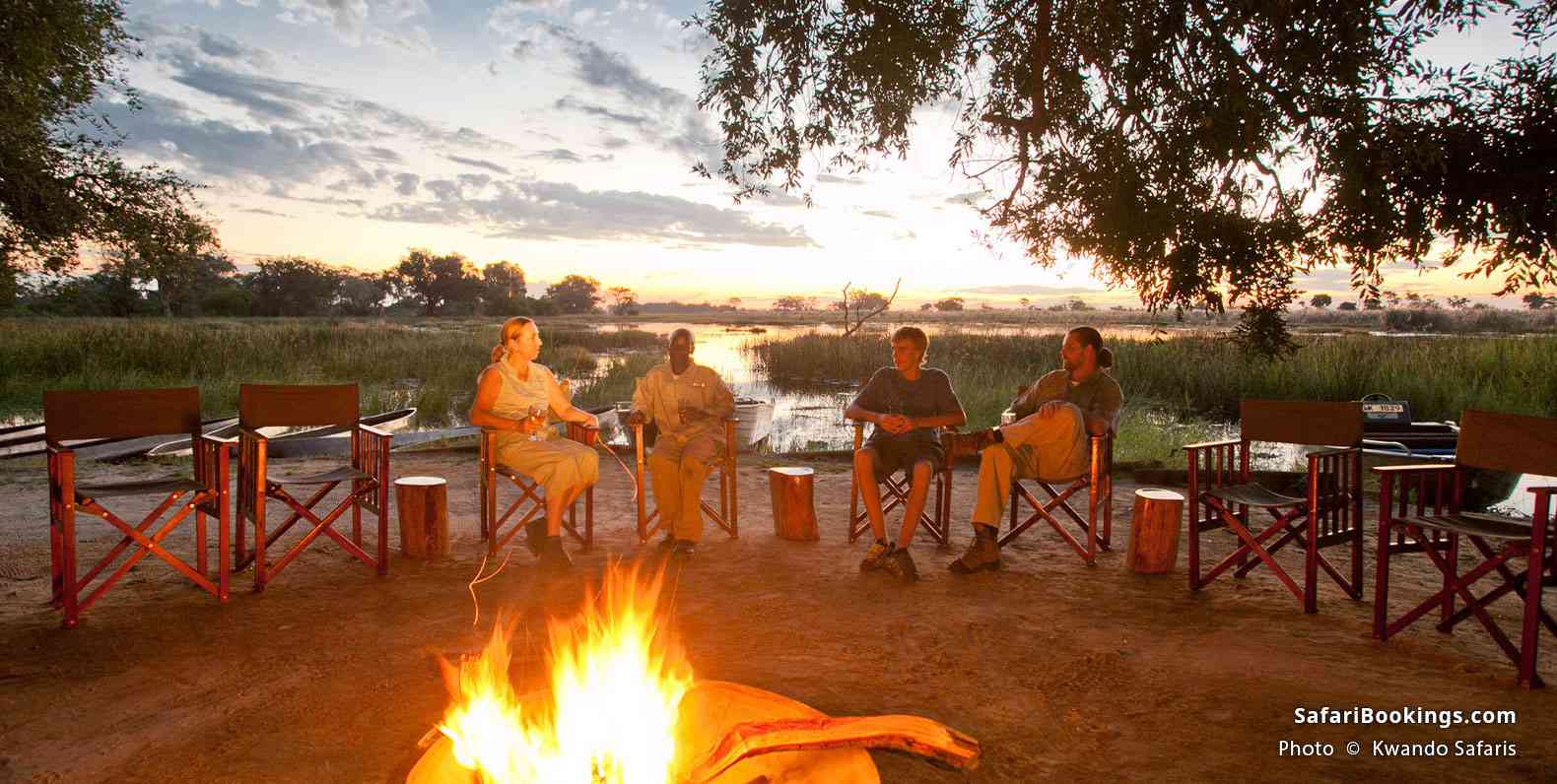 Pom Pom Camp guests sitting by the fire at dusk, with Delta in the background
