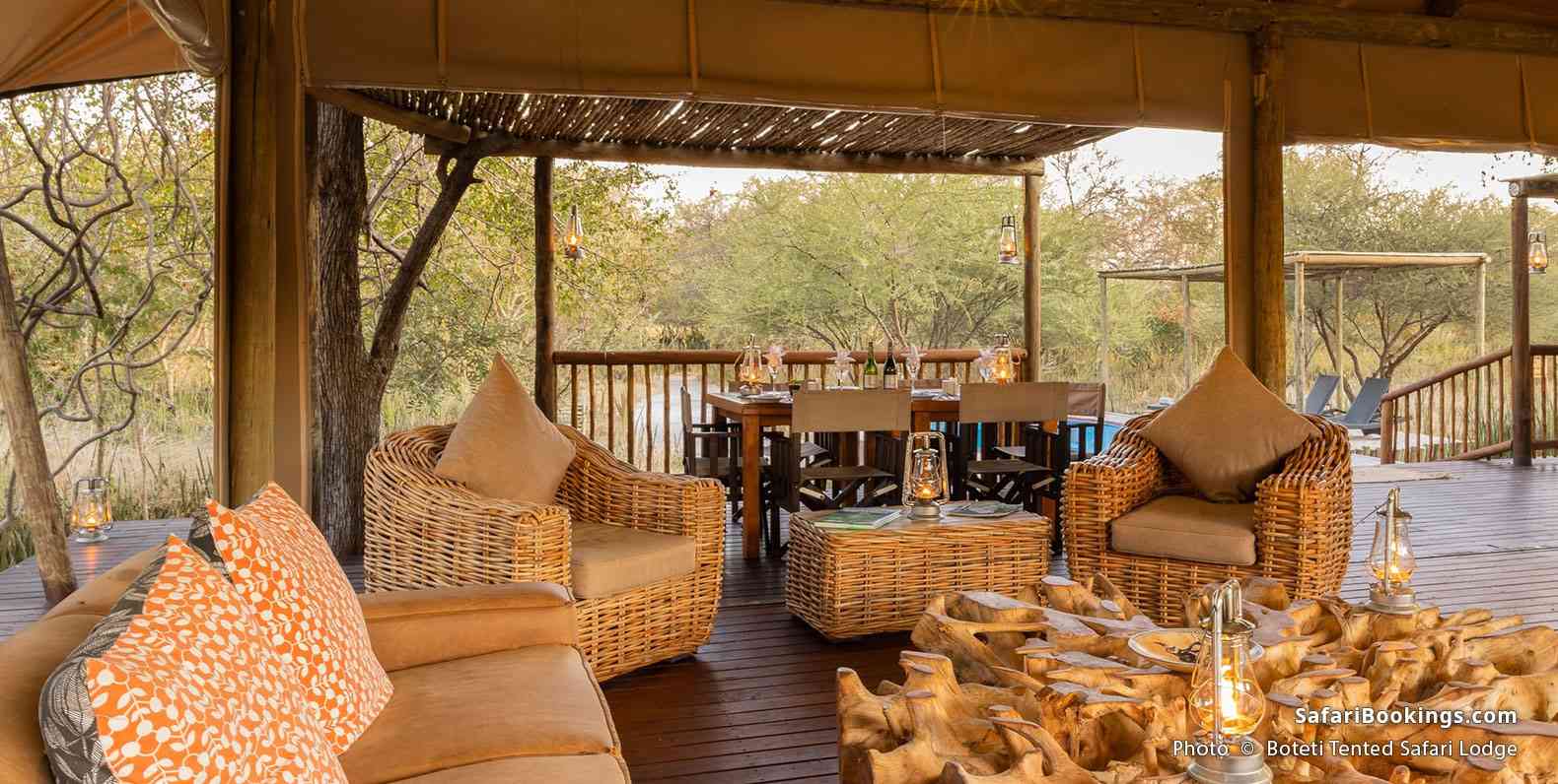 A cozy open-air lounge with wicker furniture and warm lighting overlooks the bush at Boteti Tented Safari Lodge