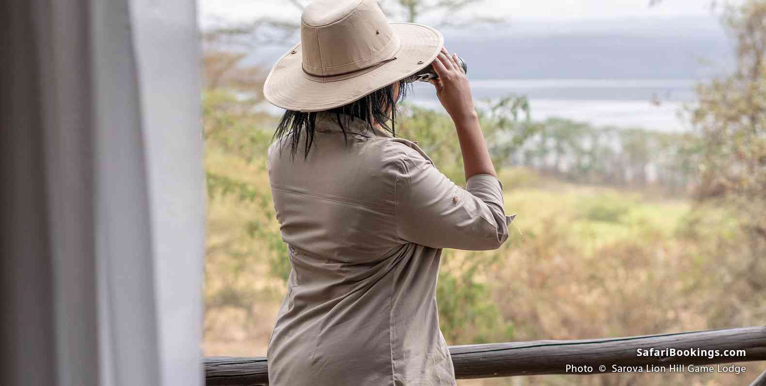 Women looking at the Lake Nakuru through binoculars from her balcony in the Sarova Lion Hill Game Lodge