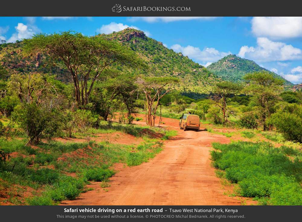 Safari vehicle driving on a red earth road in Tsavo West National Park, Kenya