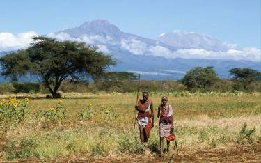 Maasai people walking in front of Mt Kilimanjaro