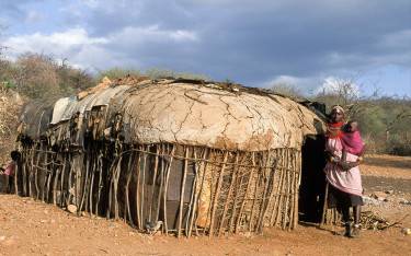 Samburu woman with baby in front of her hut