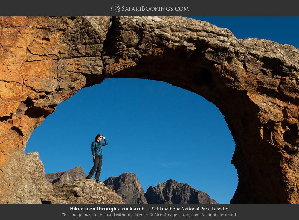 Hiker seen through a rock arch in Sehlabathebe National Park, Lesotho