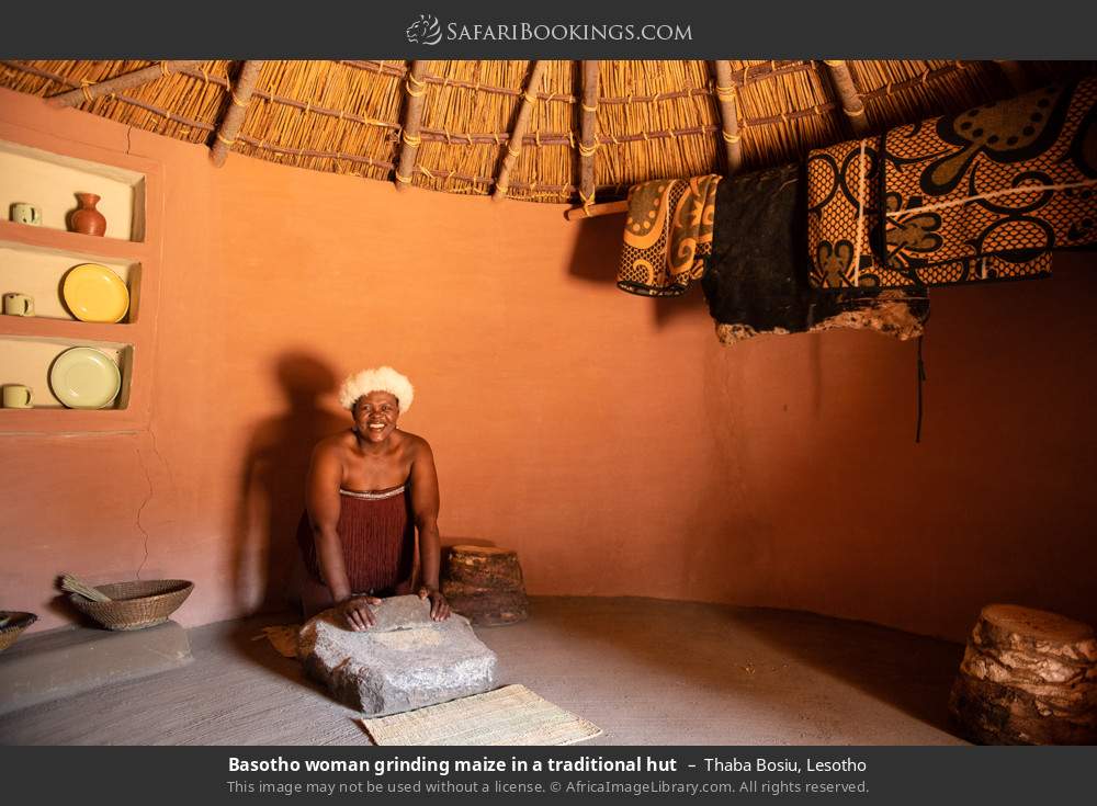 Basotho woman grinding maize in a traditional hut in Thaba Bosiu, Lesotho