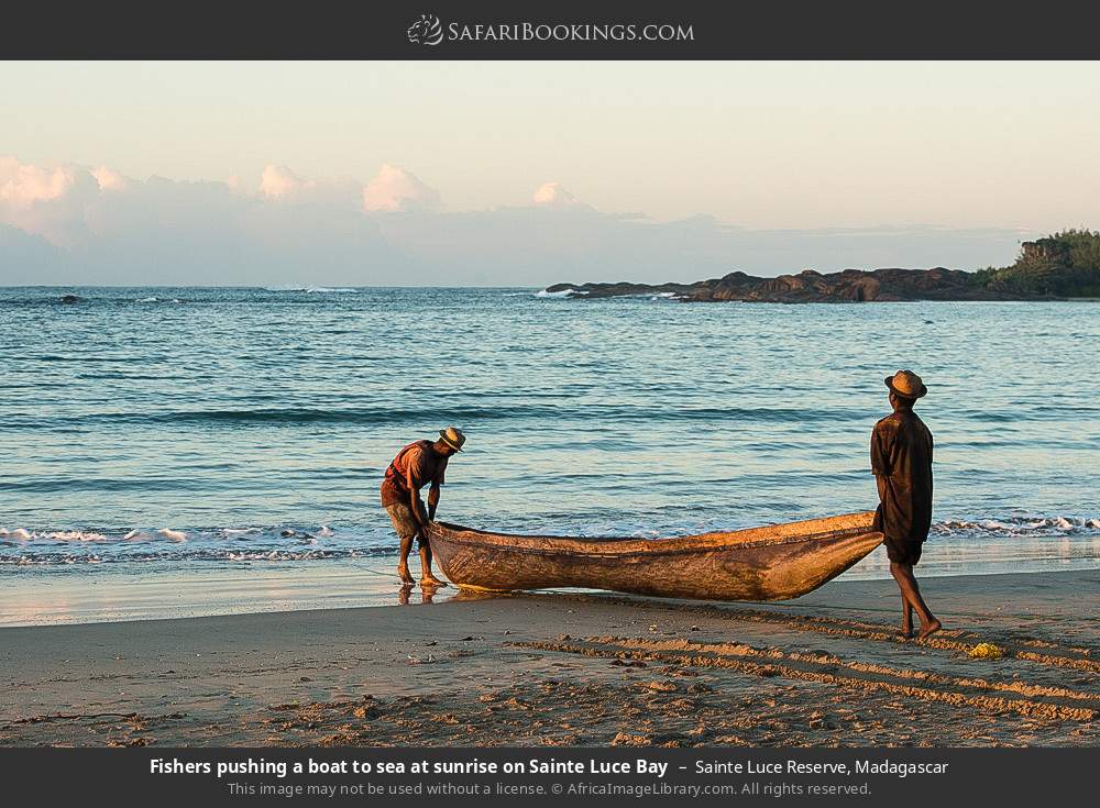 Fishers pushing a boat to sea at sunrise on Sainte Luce Bay in Sainte Luce Reserve, Madagascar