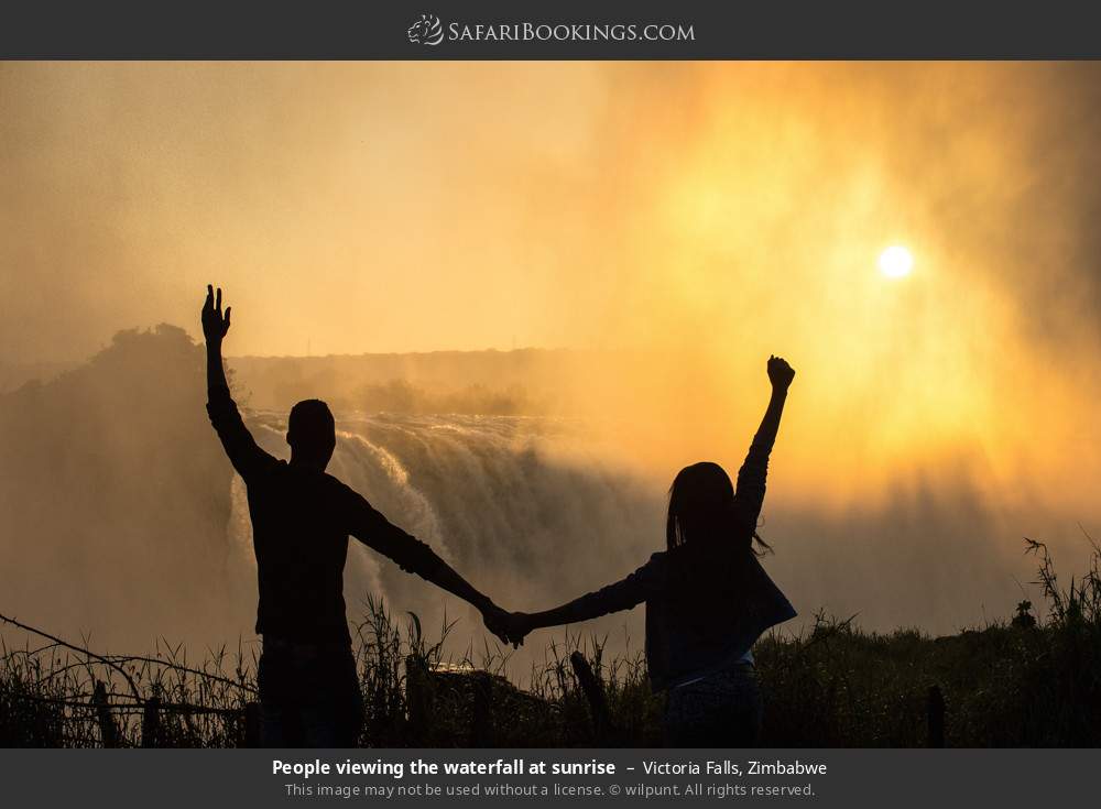 People viewing Victoria Falls at sunrise in Victoria Falls, Zimbabwe