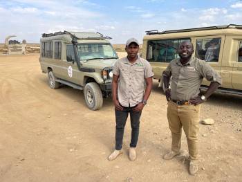 Usoke guides standing next to company vehicles